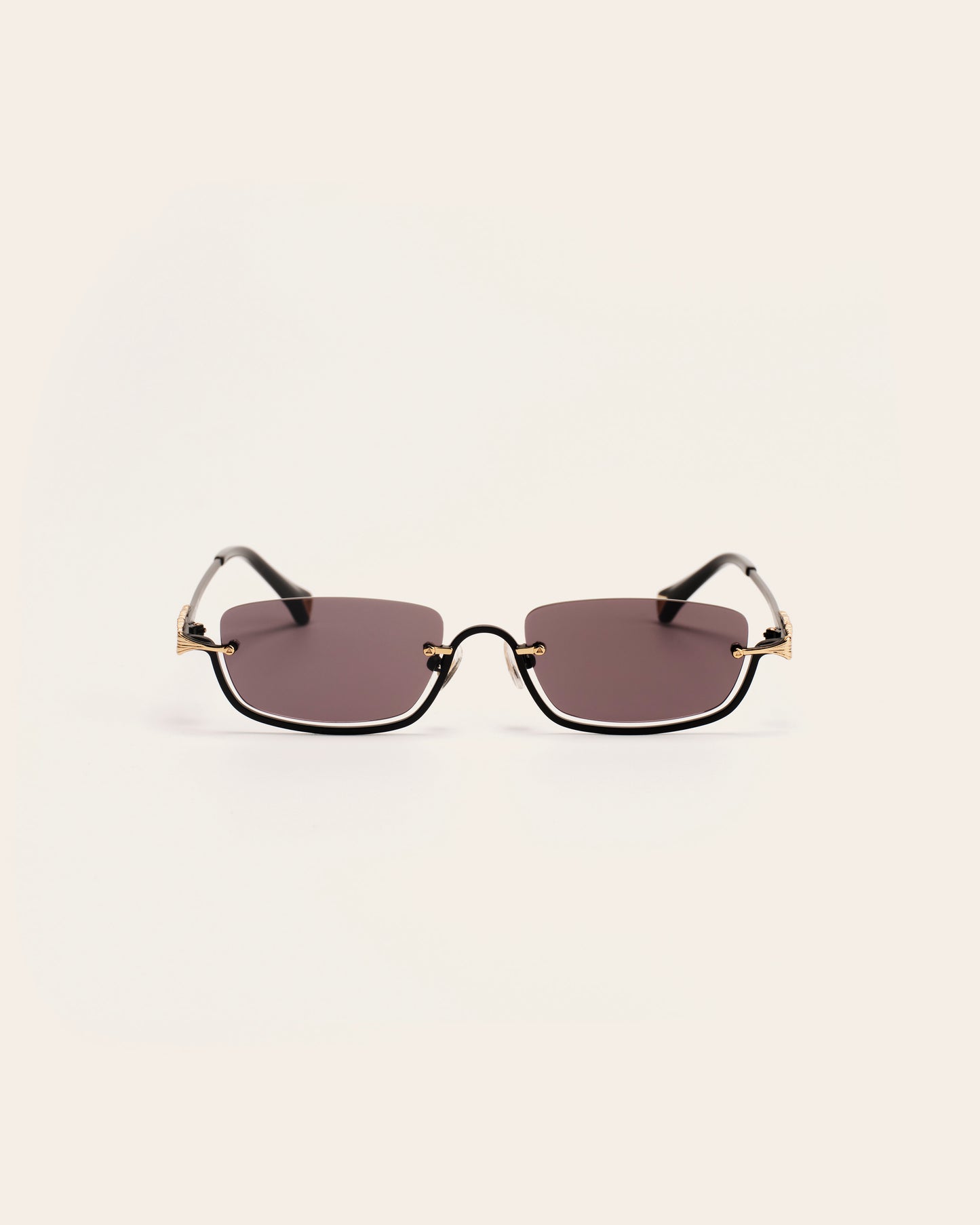 Sunglasses with gold frames and dark lenses on a light gray background