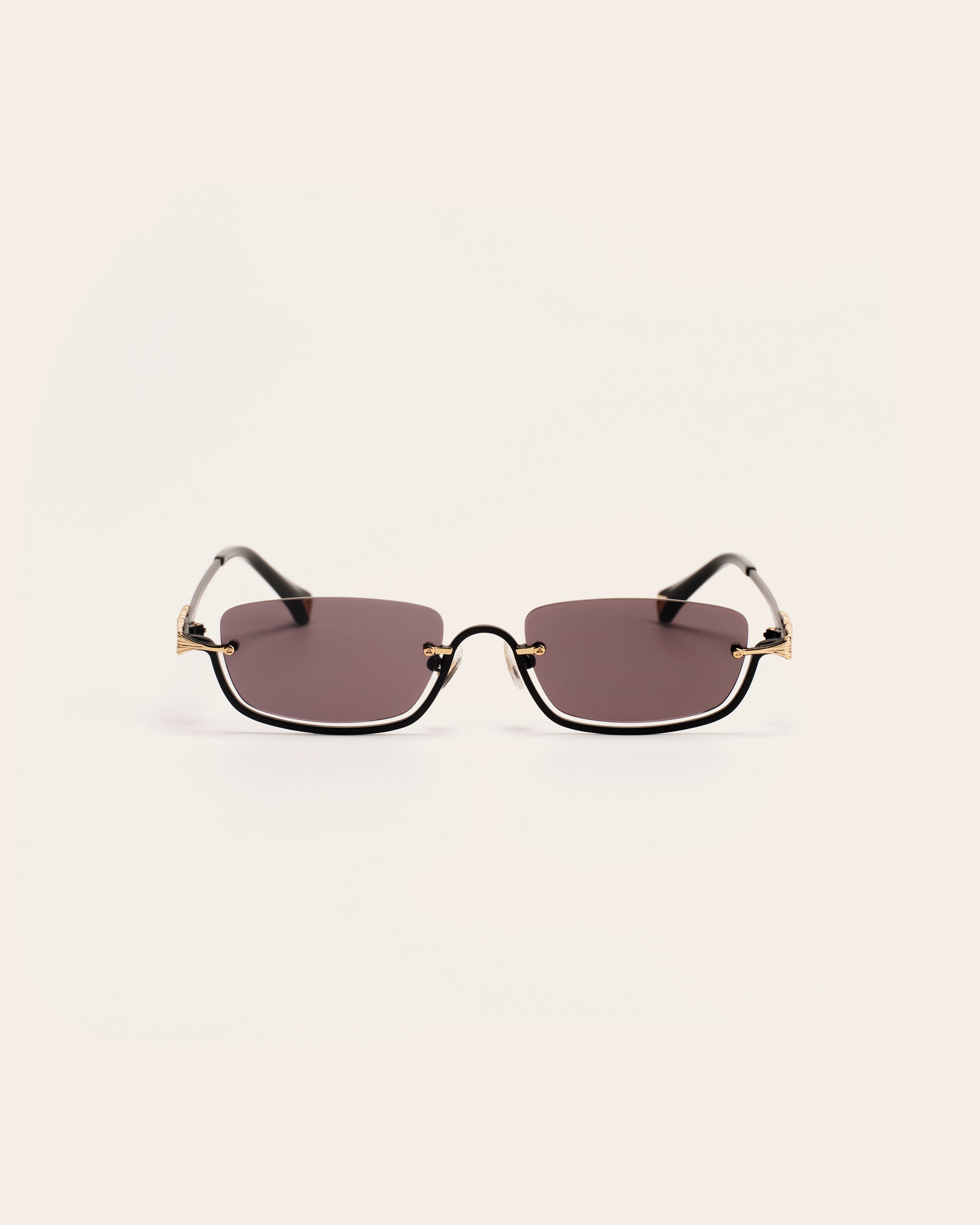 Sunglasses with gold frames and dark lenses on a light gray background