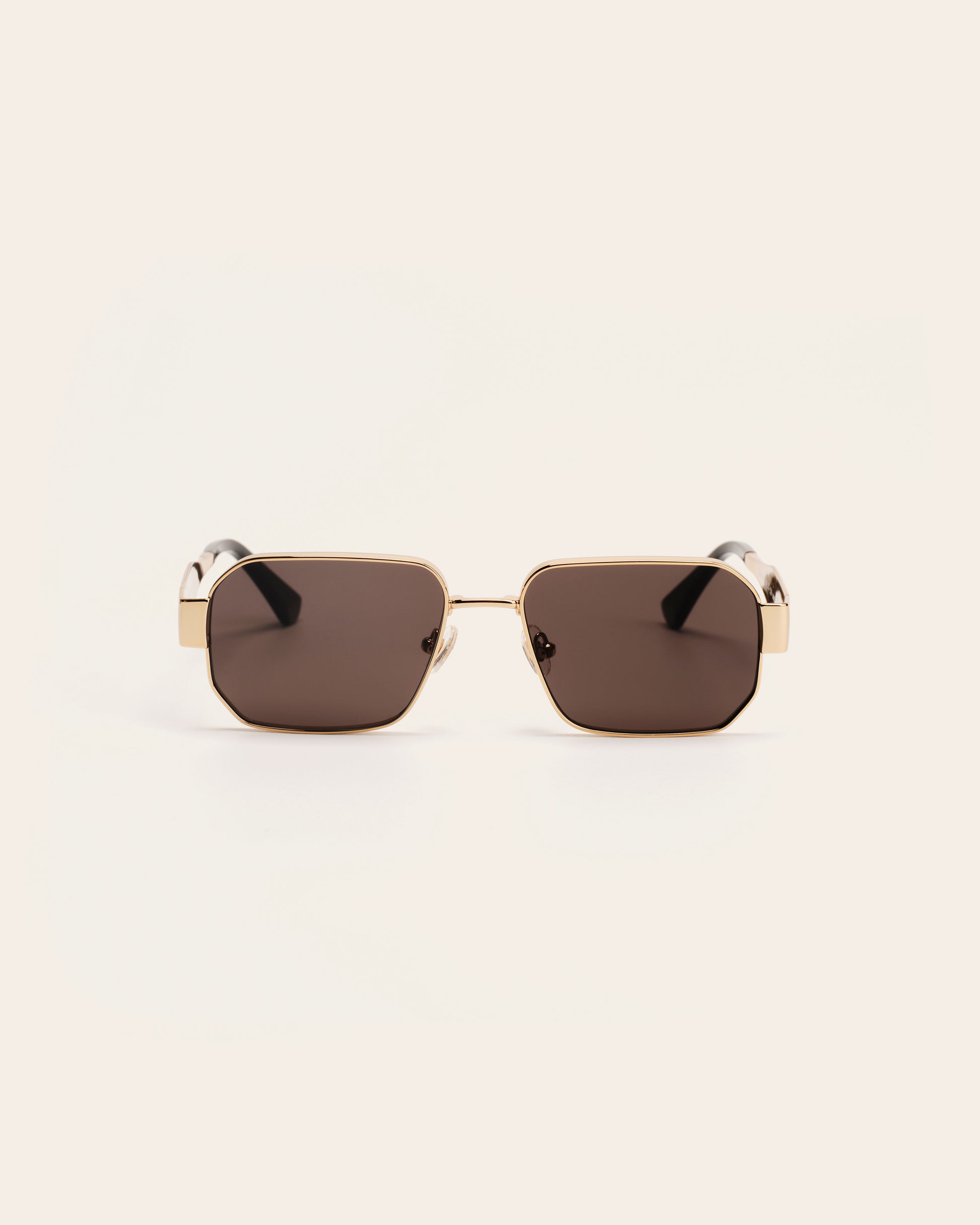 Sunglasses with gold frame and dark lenses .